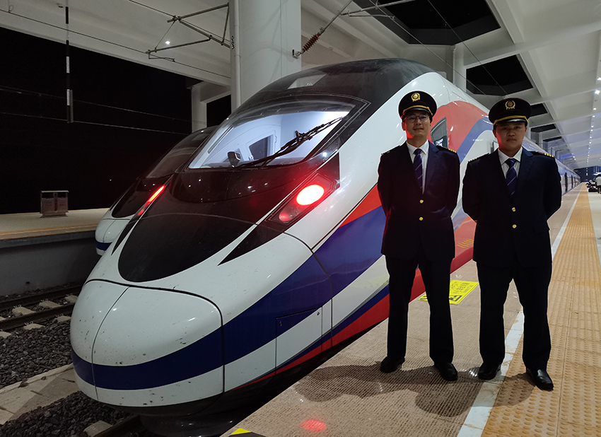 劉銀能（右一）與中國師父鄔俊鴻在動車組前合影。受訪者供圖
